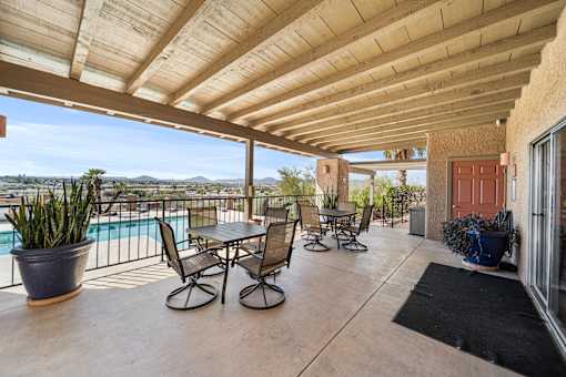 A patio with a table and chairs overlooking a pool.