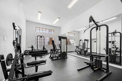 A gym with a variety of equipment including treadmills, weights, and exercise machines.