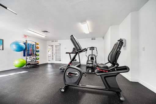 Fitness center with a stationary bike, elliptical and exercise balls.