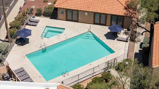 An outdoor swimming pool surrounded by a fence and trees.