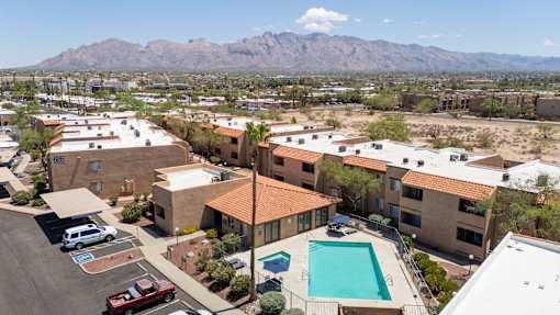 A view of a pool and apartment buildings with a mountain in the background.