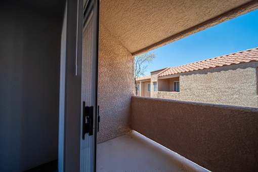 A balcony with a view of a house and trees.