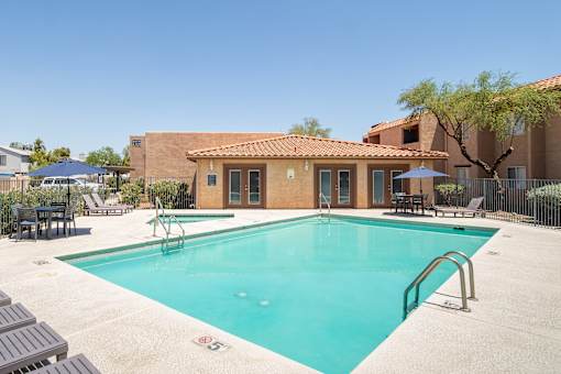 A pool with a blue umbrella and a building in the background.