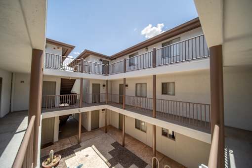A courtyard surrounded by balconies with a blue sky in the background.