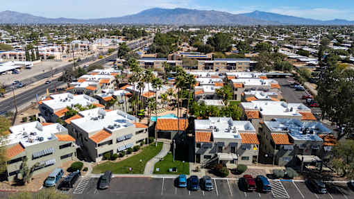 A parking lot with cars and a building with orange roofs.