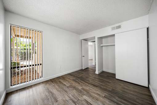 A room with a sliding door and a window with a view of a backyard.