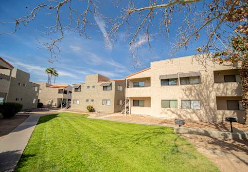 A sunny day at the apartment complex with green grass and trees.