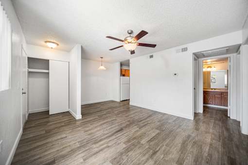A room with a ceiling fan and wooden flooring.
