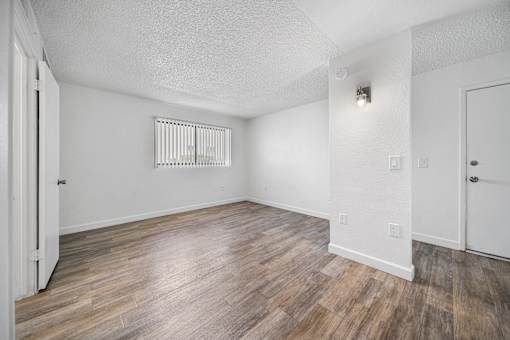 A room with wooden flooring and white walls.