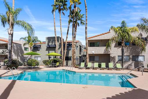 A swimming pool surrounded by palm trees and lounge chairs.