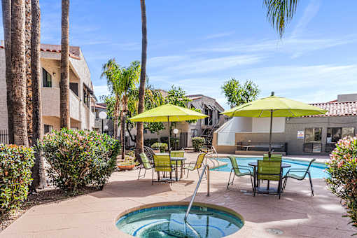 A pool area with a small pool, chairs, and umbrellas.
