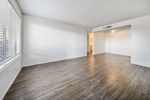 A room with wooden flooring and a door in the background.