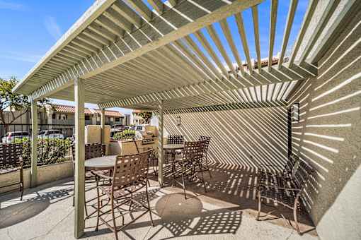 A patio with a table and chairs under a striped awning.