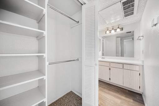 A white pantry with a white cabinet and a white shelving unit.