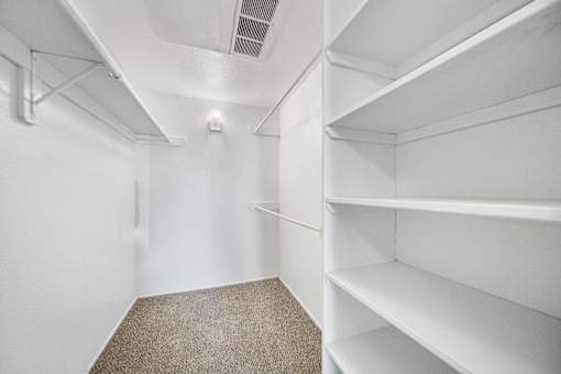 Empty white shelves in a room with carpeted floor.