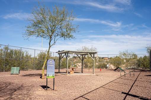 A park with a tree, a shelter, and a sign.