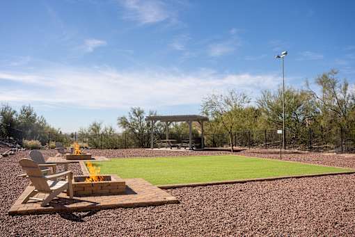 A backyard with a fire pit and a lawn.