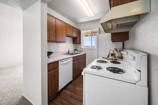 A white stove top oven with four burners is in a kitchen with wooden cabinets.
