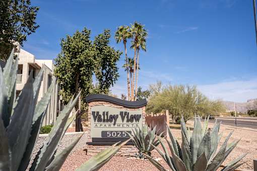A sign for Valley View Apartments is surrounded by desert plants.