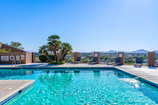 a swimming pool with palm trees and chairs at the resort on a sunny day