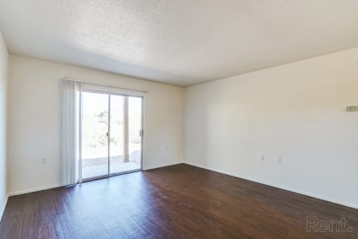 an empty living room with wood floors and a sliding glass door