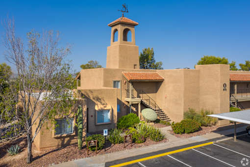 A building with a tower has a parking lot in front.