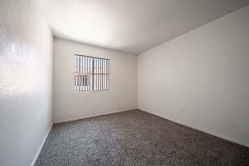 A room with a window and carpeted floor.