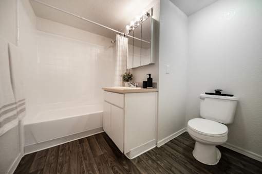 A white toilet sits next to a white bathtub in a small bathroom.