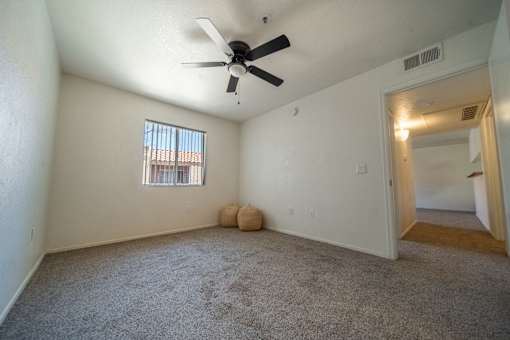 A room with a ceiling fan and a window with bars.