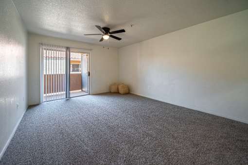 A room with a ceiling fan and carpeted floor.