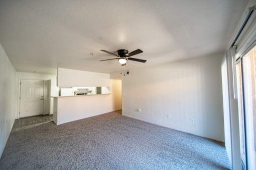 A spacious room with a ceiling fan and carpeted floor.