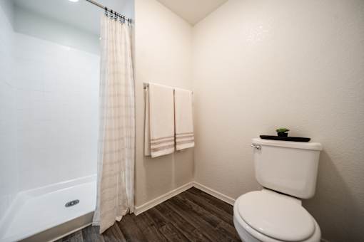 A white toilet sits in a bathroom next to a shower.