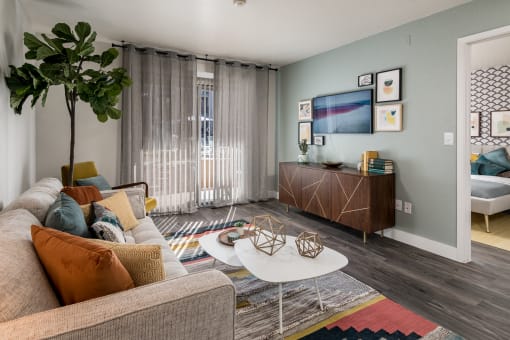 a living room with a couch coffee table and a tv in front of a sliding glass door