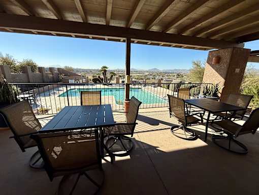 A table and chairs are set up on a patio overlooking a pool.
