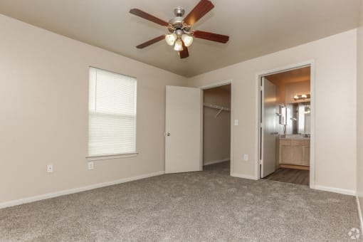 a bedroom with a ceiling fan and a door to a bathroom