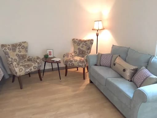 A living room with a grey couch, two chairs and a small table.