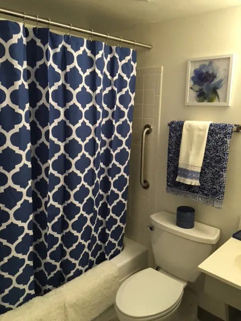 A blue and white shower curtain with a white toilet and a blue towel.