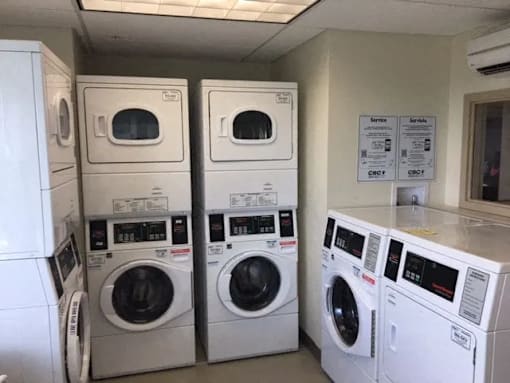 A row of white front load washing machines in a laundromat.