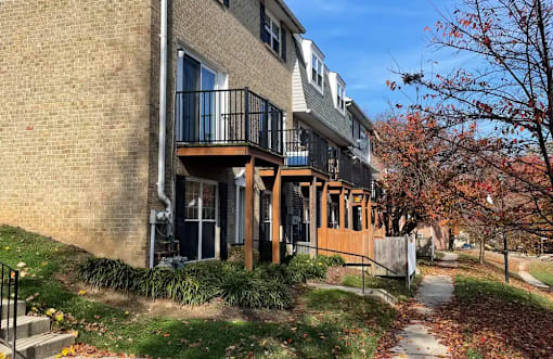 A brick building with a balcony and a tree with red leaves.