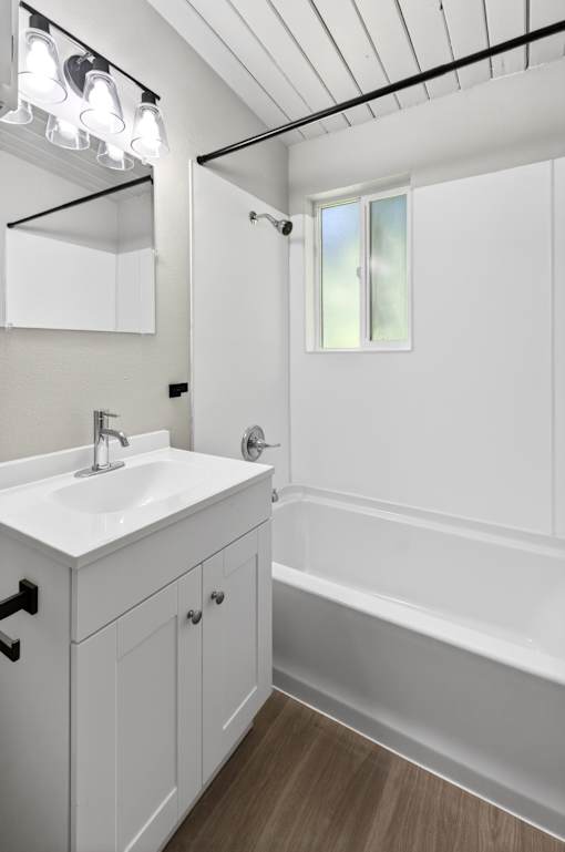 A white bathroom with a sink, mirror, and bathtub.