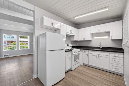 A white kitchen with a refrigerator, stove, and cabinets.