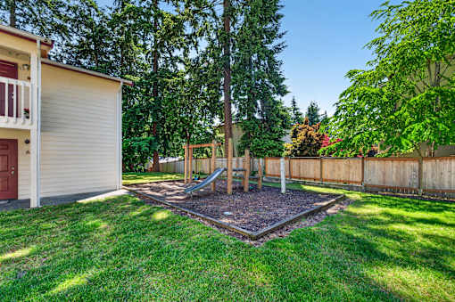 A backyard with a playground and a fence.