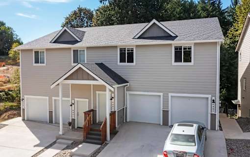 A house with a grey roof and a car parked in front.