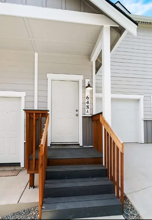 A white door with the numbers 648 on it is on the front porch of a house.