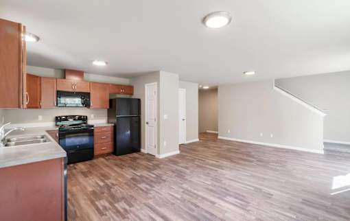 A kitchen with wooden floors and a black refrigerator.