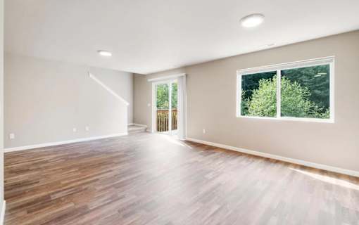 A spacious room with wooden flooring and a large window.