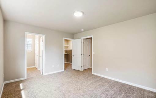 A spacious room with carpeted floor and white walls.