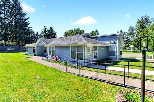 A house with a grey roof and a fence in front of it.