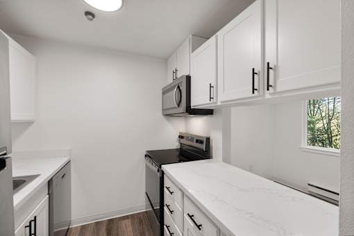 A kitchen with white cabinets and a black stove top oven.