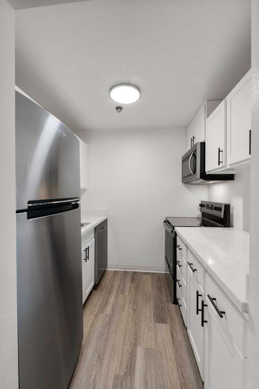 Kitchen with a stainless steel refrigerator and white cabinets. 1bd FP